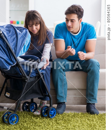 Young parents with their newborn baby in baby pram sitting on th 80564165