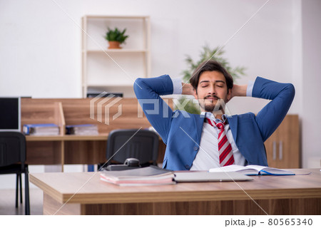 Young male employee sitting at workplace Young male employee sitting at workplace 80565340