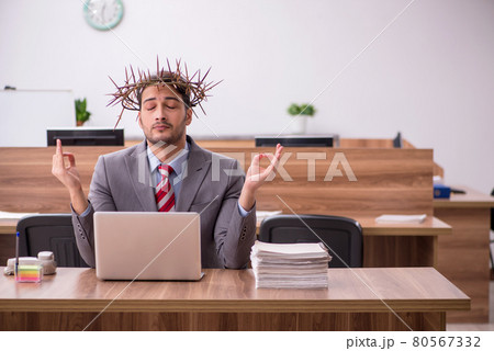 Young male employee wearing prickly wreath on head 80567332