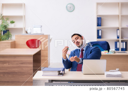 Young male employee suffering from toothache at workplace Young male employee suffering from toothache at workplace 80567745