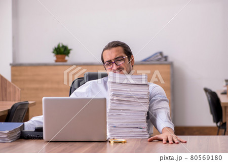 Young male employee unhappy with excessive work in the office Young male employee unhappy with excessive work in the office 80569180