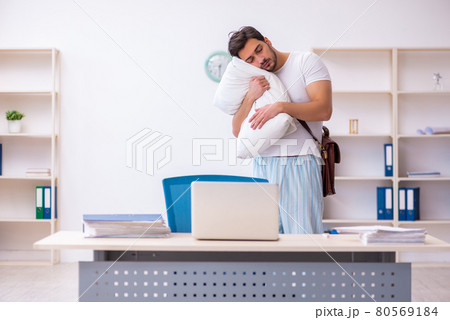 Young male employee coming to work straight from bed Young male employee coming to work straight from bed 80569184