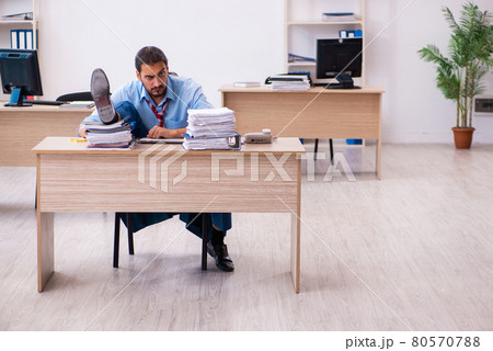 Young male employee unhappy with excessive work in the office Young male employee unhappy with excessive work in the office 80570788