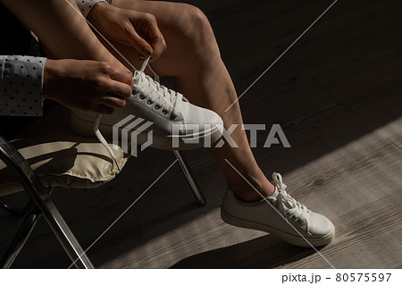 Woman put on new white leather sneakers Woman put on new white leather sneakers 80575597
