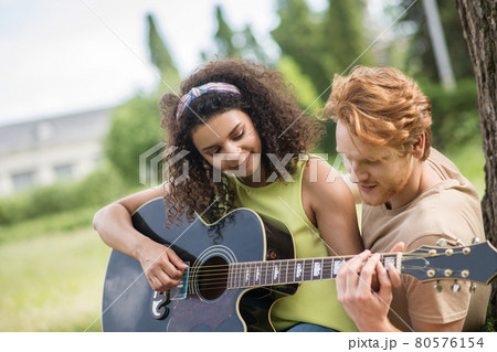Guy teaching his girlfriend to play guitar Guy teaching his girlfriend to play guitar 80576154