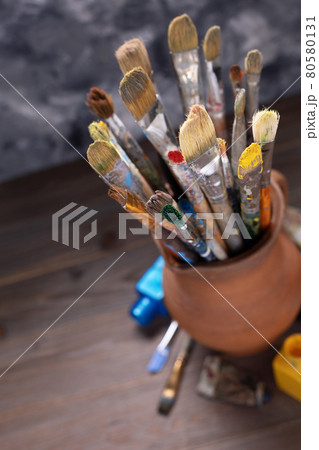 Paint brush in clay jug and used tubes on wooden table background . Paintbrush for art painting Paint brush in clay jug and used tubes on wooden table background . Paintbrush for art painting 80580131