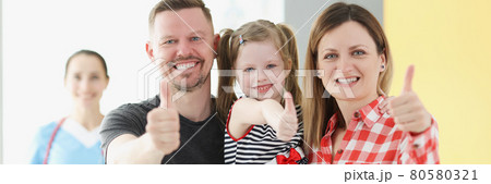 Smiling family doing thumbs up gesture in background is doctor 80580321