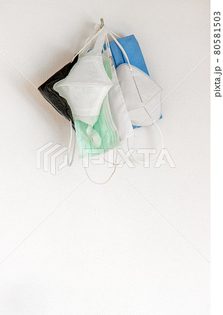 The used protective face masks hanging on a hook on a white wall, close up view The used protective face masks hanging on a hook on a white wall, close up view 80581503