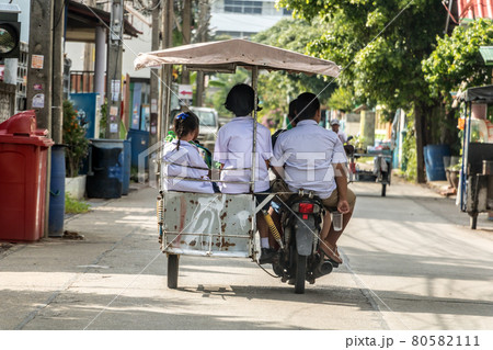 Children are coming back from school. Group of children riding a motorcycle - tricycle, Thailand. 80582111