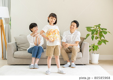 リビングでモデルポーズをする女の子とパパとママの3人家族のポートレートの写真素材 リビングでモデルポーズをする女の子とパパとママの3人家族のポートレートの写真素材