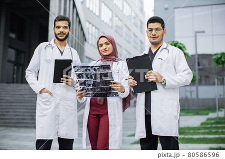 Three doctors, Muslim lady in hijab and two Arabian men, working in front of the clinic 80586596