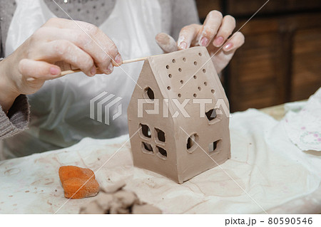 Women's hands knead clay, drawing elements of the product. Production of ceramic products at the master class on ceramics. Women's hands knead clay, drawing elements of the product. Production of ceramic products at the master class on ceramics. 80590546