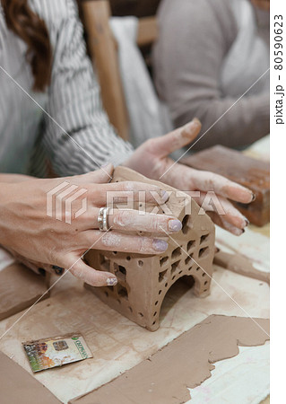 Women's hands knead clay, drawing elements of the product. Production of ceramic products at the master class on ceramics. 80590623