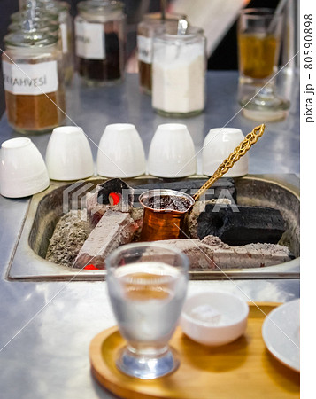 Cooking Turkish coffee on coals in a traditional way with water and Turkish delight. Mobile coffee shop on the street. Cooking Turkish coffee on coals in a traditional way with water and Turkish delight. Mobile coffee shop on the street. 80590898