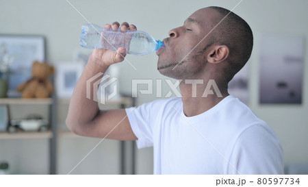 Close up of African Man Drinking Water at Home Close up of African Man Drinking Water at Home 80597734