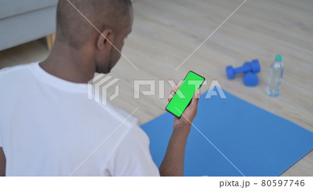 Rear View of African Man using Smartphone with Chroma Key Screen on Yoga Mat 80597746