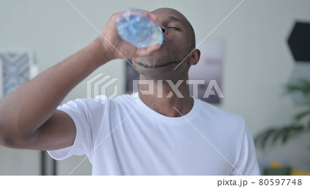 Close up of African Man Drinking Water at Home 80597748