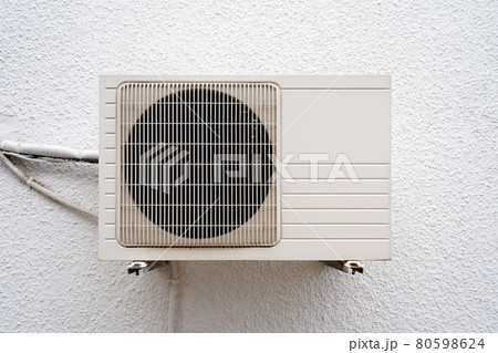 White air conditioner hangs on a white wall. Close-up White air conditioner hangs on a white wall. Close-up 80598624