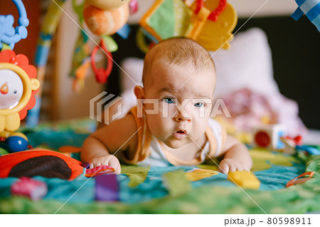Infant lies on his tummy surrounded by soft toys and rattles Infant lies on his tummy surrounded by soft toys and rattles 80598911