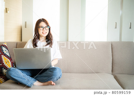 自宅でパソコンをする笑顔の眼鏡女子 80599159