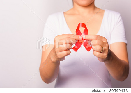 Closeup of female with red ribbon Support HIV AIDS on hands 80599458