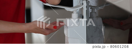 Woman hand pushes pump head onto bottle of gel, soap or hand sanitizer and holds drops of gel in her hand Woman hand pushes pump head onto bottle of gel, soap or hand sanitizer and holds drops of gel in her hand 80601208