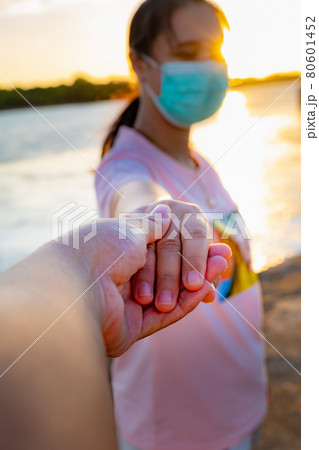 Young people holding hands but still wearing masks show their relationship by focusing on their hands. Young people holding hands but still wearing masks show their relationship by focusing on their hands. 80601452