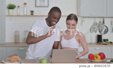Mixed Race Couple Talking on Video Call in Kitchen 80602870