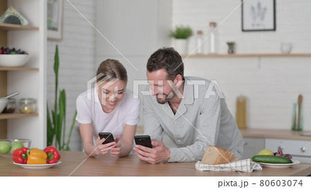 Happy Couple using Smartphone in Kitchen Happy Couple using Smartphone in Kitchen 80603074