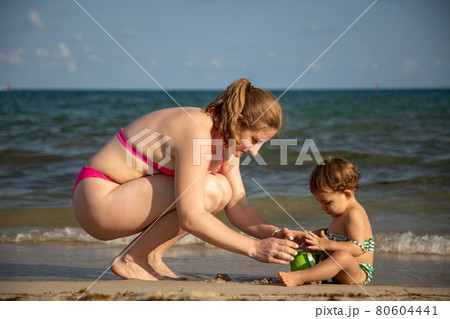 mothers Day. mom and baby enthusiastically play in the sand on the seashore 80604441