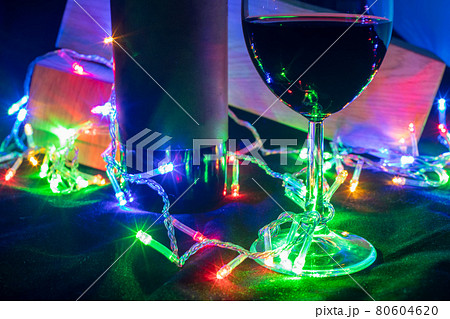 wine glass and bottle in shining garland bokeh on black background wine glass and bottle in shining garland bokeh on black background 80604620