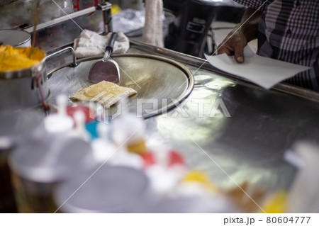 process for the preparation of tasty traditional Thai pancakes on a street counter. male hands fry a pancake in oil. local specialty process for the preparation of tasty traditional Thai pancakes on a street counter. male hands fry a pancake in oil. local specialty 80604777