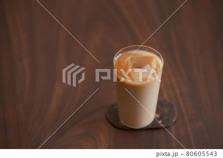 Ice coffee wih milk in tumbler glass on black walnut table Ice coffee wih milk in tumbler glass on black walnut table 80605543