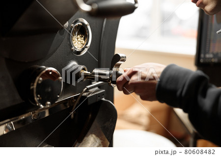 Young specialist worker is roasting coffee in hangar Young specialist worker is roasting coffee in hangar 80608482