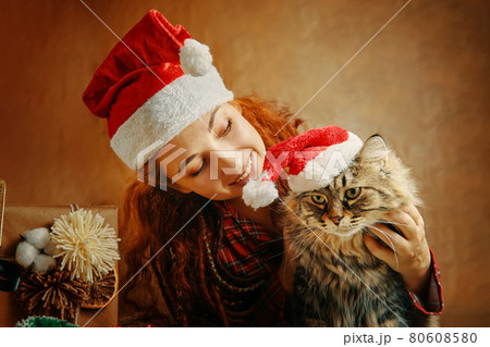 Woman in Santa Claus hat with cat in Christmas hat. Woman in Santa Claus hat with cat in Christmas hat. 80608580
