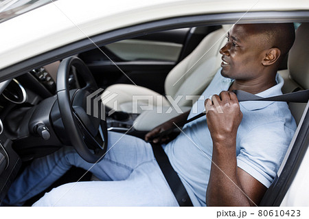 Black man driver fasten seat belt, side view Black man driver fasten seat belt, side view 80610423