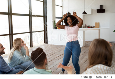 Positive diverse friends playing guess who game, showing pantomime riddles or charades, laughing, having fun together Positive diverse friends playing guess who game, showing pantomime riddles or charades, laughing, having fun together 80610713