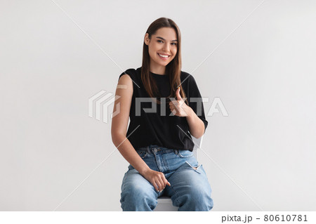 Portrait of millennial woman with adhesive bandage on her arm after coronavirus vaccination showing thumb up gesture Portrait of millennial woman with adhesive bandage on her arm after coronavirus vaccination showing thumb up gesture 80610781