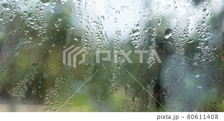 Rain drops on glass window. Raindrops falling from glass material. Abstract nature background. Copy space for text. Focus on foreground. 80611408