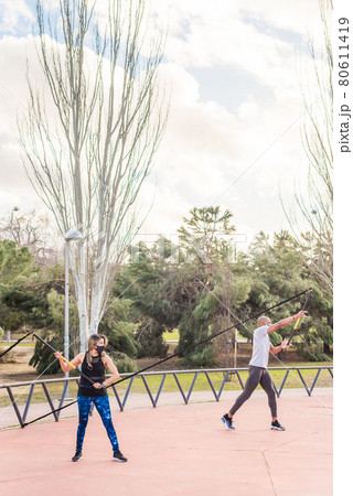 Fitness couple exercising with a trx fitness strap in the park. Fitness couple exercising with a trx fitness strap in the park. 80611419