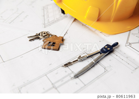 Construction plans with yellow helmet, house keys and drawing tools on a table 80611963