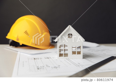 Construction plans with yellow helmet and model of house Construction plans with yellow helmet and model of house 80611974