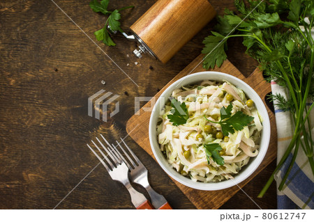 Salad with fresh cabbage, calamary, cucumber and green peas in a bowl on a rustic table. Top view flat lay background. Copy space. 80612747