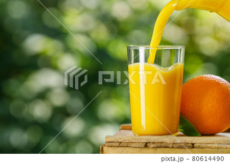 fresh orange juice pouring into glass outdoors fresh orange juice pouring into glass outdoors 80614490