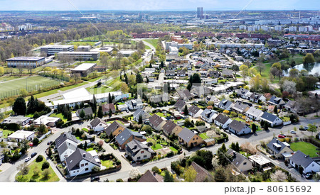 Aerial view of a housing estate on the outskirts of the city of Wolfsburg in Germany with a school in the background and factories on the horizon. 80615692