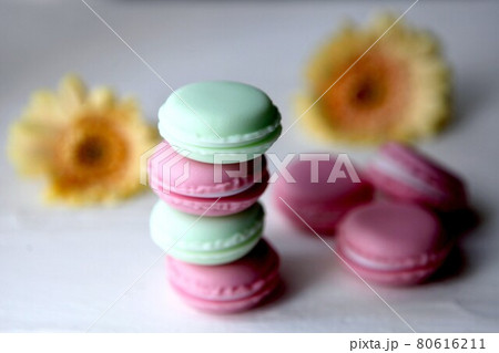 Tasty macaroon colourful texture. A french sweet delicacy, colorful macaroons variety closeup with flowers on white backround. 80616211