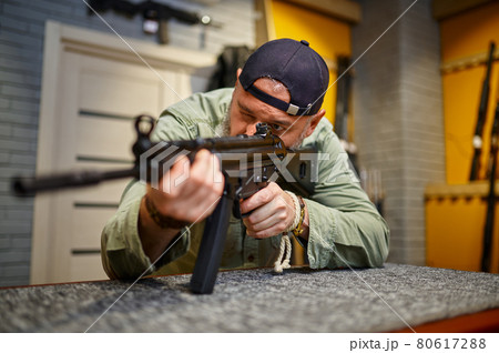 Bearded man checks the rifle scope in gun store Bearded man checks the rifle scope in gun store 80617288