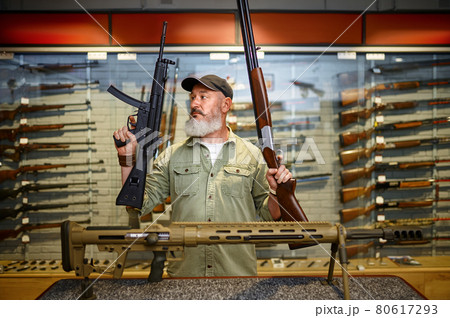 Happy male hunter with two rifles in gun store Happy male hunter with two rifles in gun store 80617293