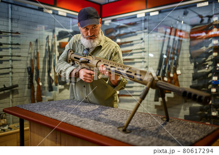 Bearded man reload powerful rifle in gun store Bearded man reload powerful rifle in gun store 80617294