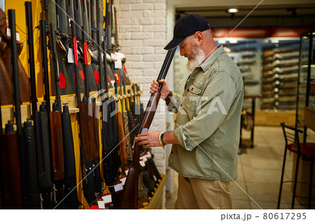 Hunter at showcase with hunting rifles, gun store Hunter at showcase with hunting rifles, gun store 80617295